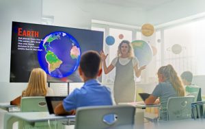 An educator guiding students with diverse abilities through an interactive STEM activity, using tactile models and digital tools designed for accessibility.